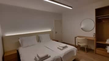 Habitación de hotel con cama, mesitas de noche, escritorio, silla, armario y espejo.