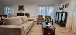 A living room with a beige sofa, two brown armchairs, a glass coffee table, and a cabinet with glass doors. - House 'Casa Casais' with private terrace, private garden and Wi-Fi (Chafé)