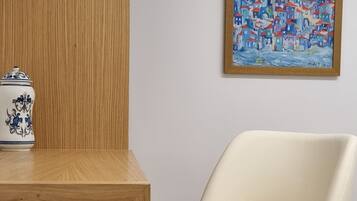 A wooden desk with a ceramic object and a white chair with wooden legs in a room with wooden flooring.
