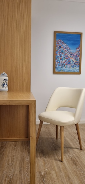 A wooden desk with a ceramic object and a white chair with wooden legs in a room with wooden flooring. - House 'Casa Casais' with private terrace, private garden and Wi-Fi (Chafé)