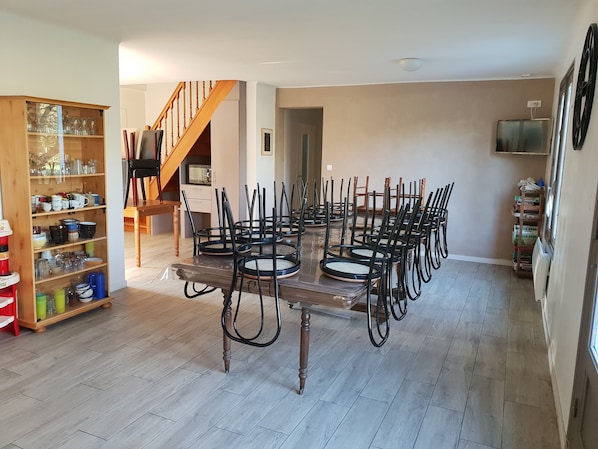Un comedor con una mesa y sillas de madera, una estantería con cristalería y una escalera.