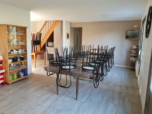 Un comedor con una mesa y sillas de madera, una estantería con cristalería y una escalera.
