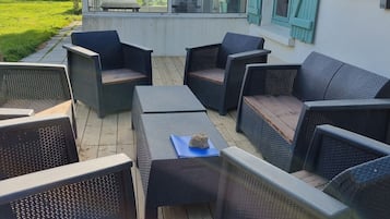 An outdoor deck with wicker furniture and a glass enclosure.