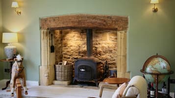 A cozy room with a stone fireplace, a wooden chair, a globe, and a lamp on a side table.