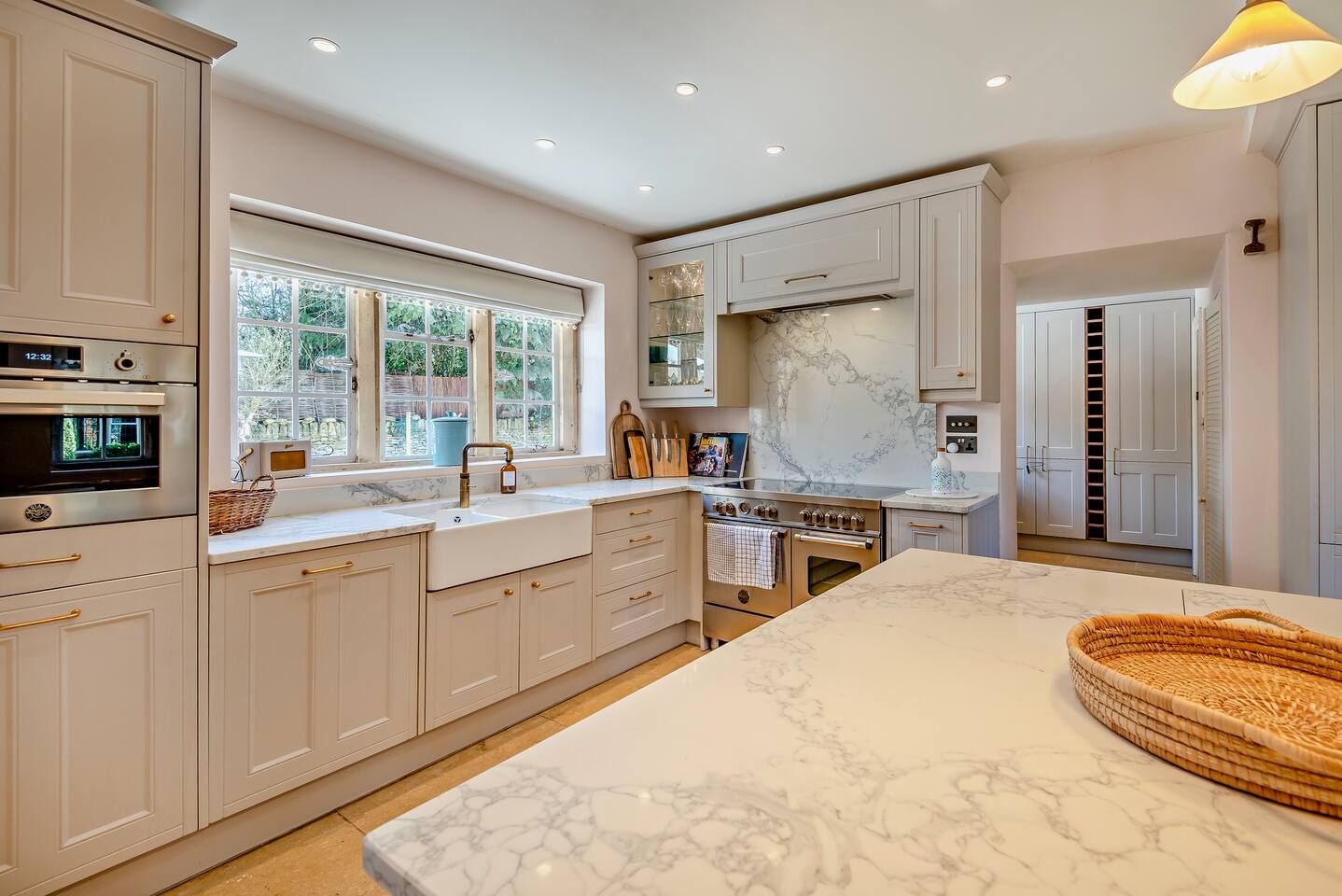 A modern kitchen with white cabinetry, a marble countertop, and a built-in oven.