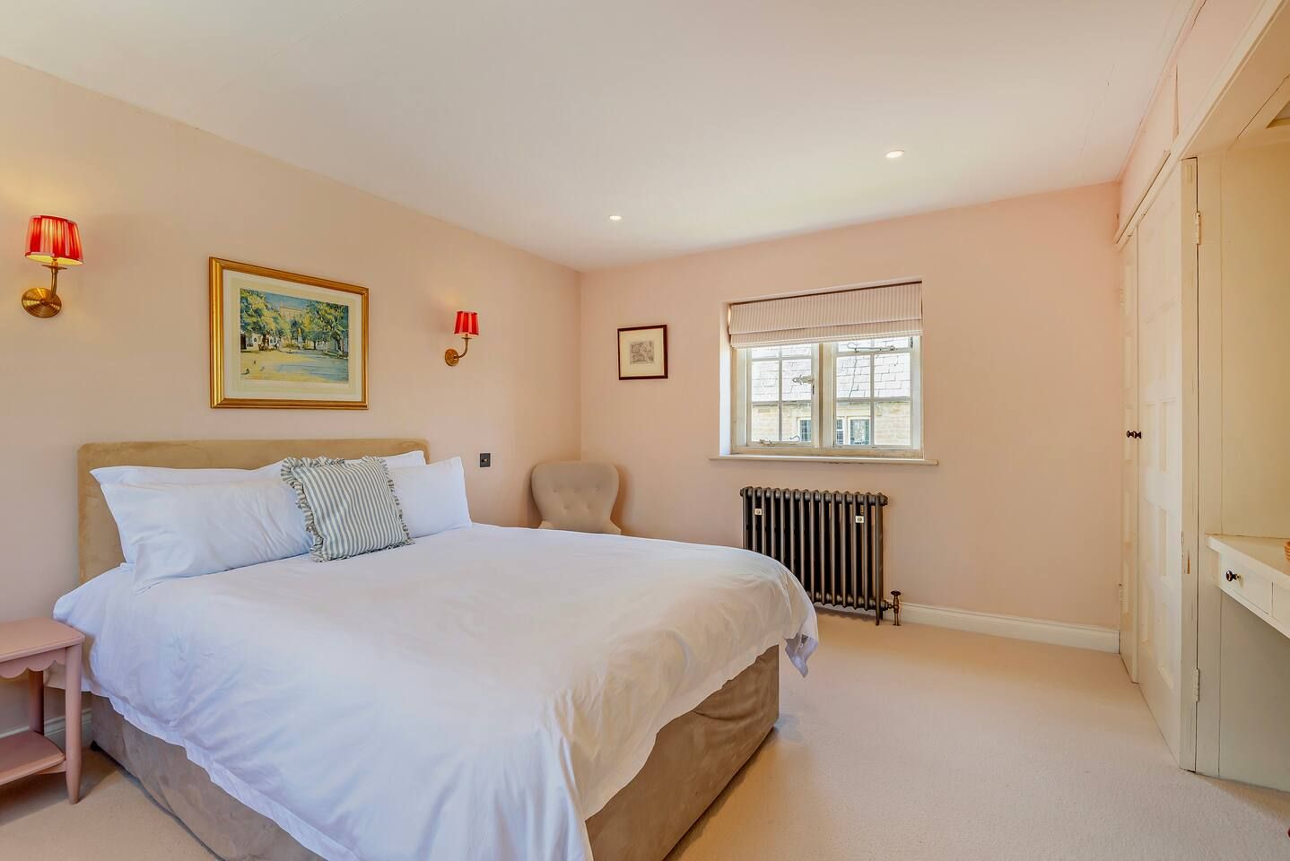 A bedroom with a bed, a chair, a radiator, and a window.