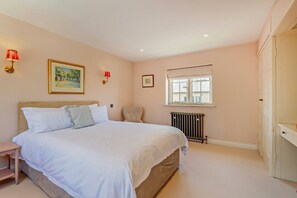 A bedroom with a bed, a chair, a radiator, and a window.