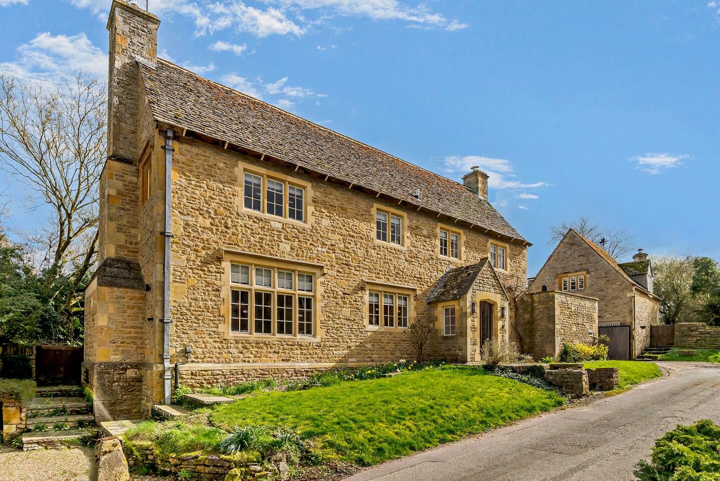 A stone house with a traditional design, featuring a prominent chimney and multiple windows.