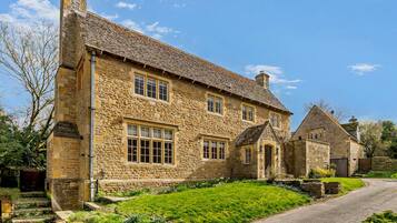 A stone house with a traditional design, featuring a prominent chimney and multiple windows.