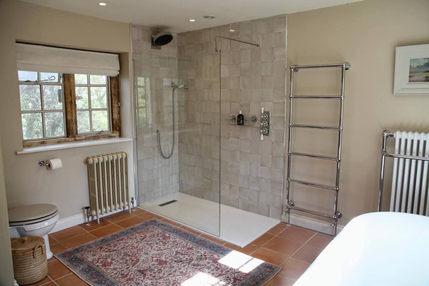 A bathroom with a glass-enclosed shower, a white toilet, a radiator, and a towel rack.