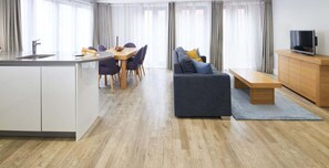A modern living room with a sofa, a dining table with chairs, a kitchen area with a sink, and a television. - City Double Viii - 2BR Home With Terrace in the City (London)