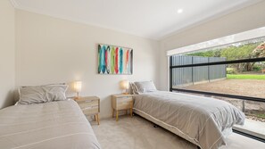 Een slaapkamer met twee bedden, een groot raam en een kleurrijk abstract schilderij.
