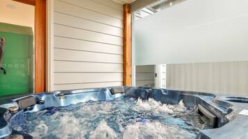 Een hottub met een houten omlijsting, een groene deur en een witte muur.