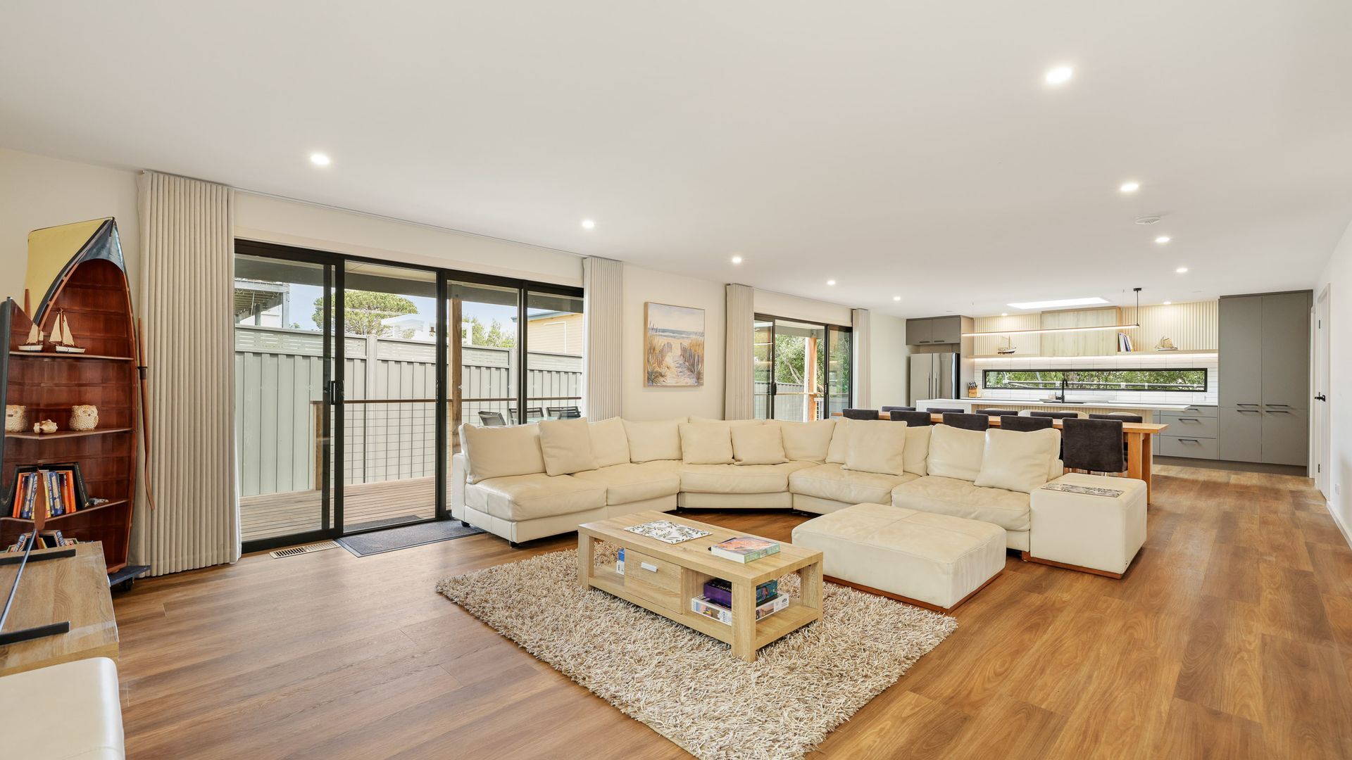 A spacious living area with a large L-shaped sofa, a wooden coffee table, and a bookshelf.