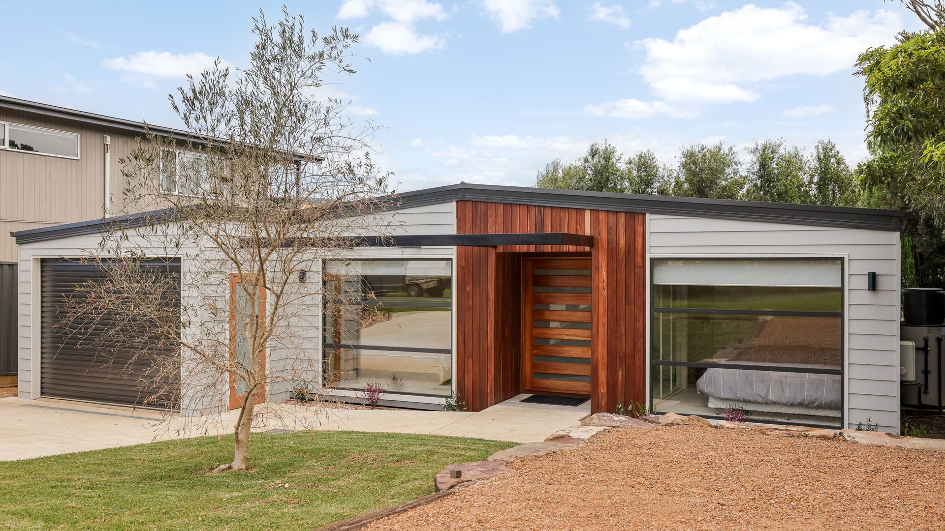 A modern single-story house with a garage, a wooden door, and large windows.