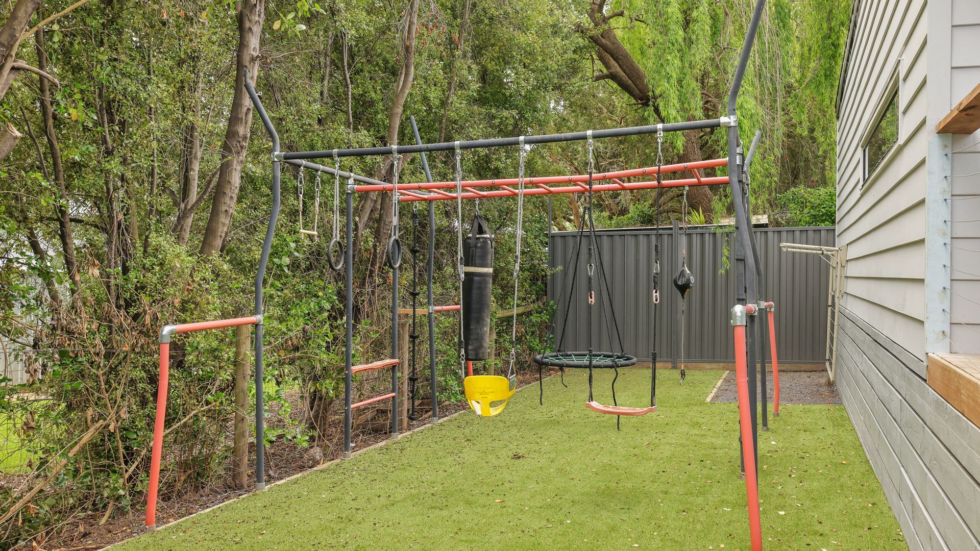 Ein Spielplatz mit Schaukeln, einer Kletterkonstruktion und einem kleinen Trampolin.