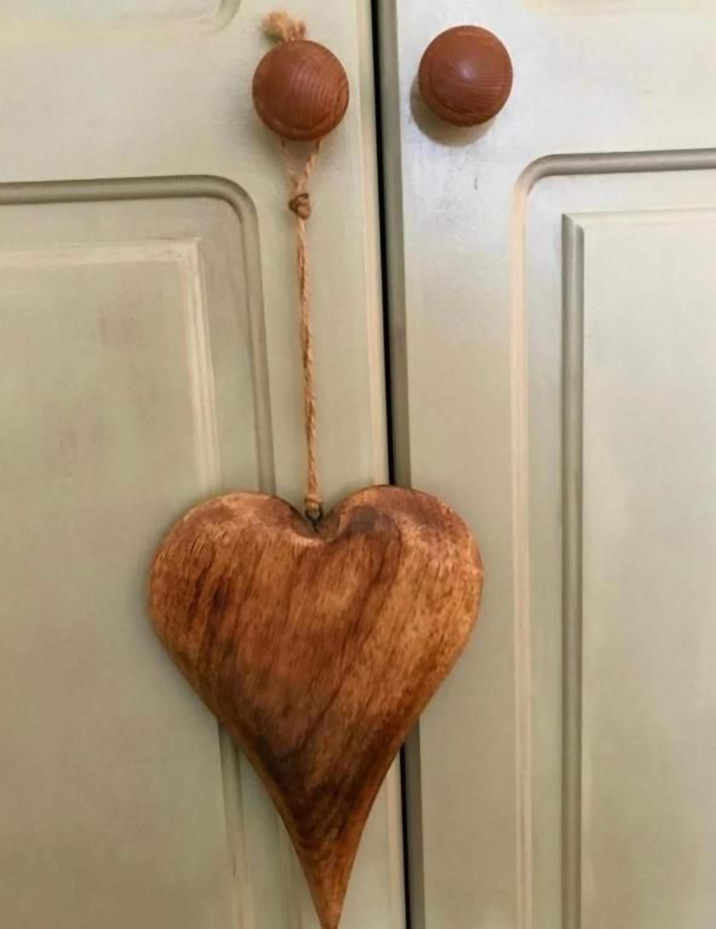 A wooden heart-shaped decoration hanging from a door handle.