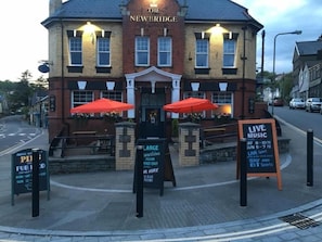 A pub named 'The Newbridge' with outdoor seating and a sign advertising live music events.