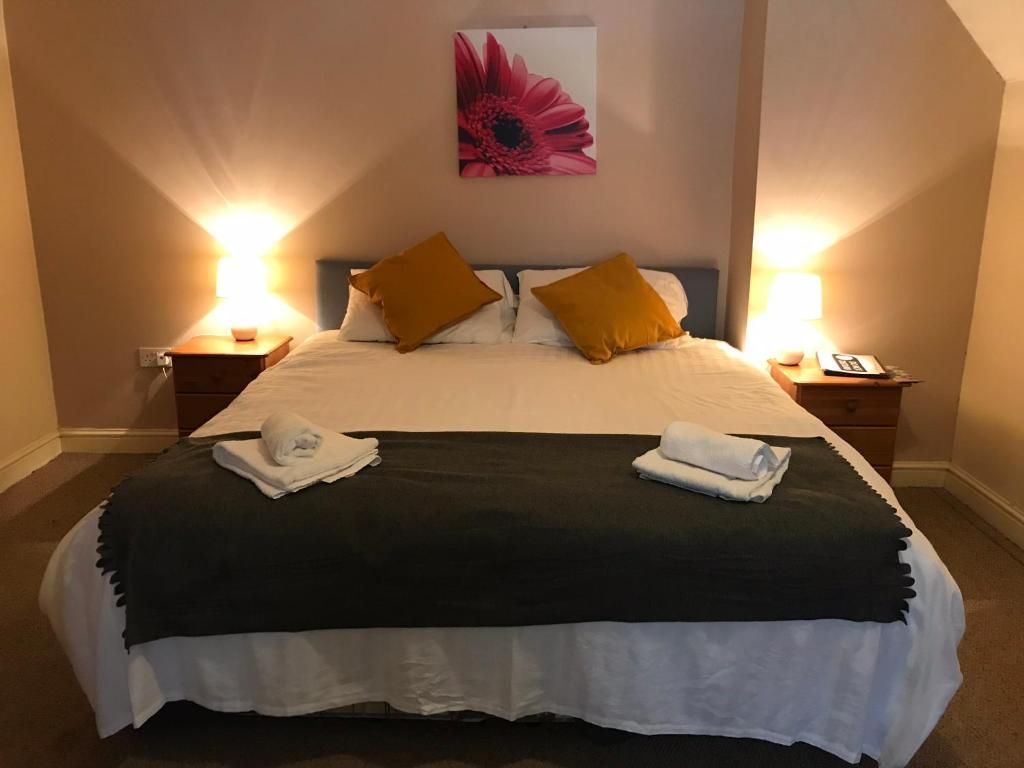 Ein Hotelzimmer mit einem großen Bett, zwei Nachttischen, einer Wandlampe und einem Blumenbild.