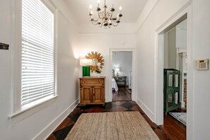 A hallway with a wooden cabinet, a chandelier, and a rug. - Betty (Mobile)