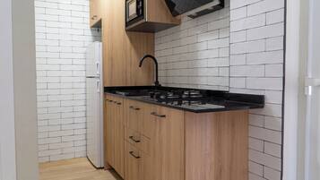 Een kleine keuken met een ingebouwde kookplaat, een spoelbak en houten keukenkastjes.