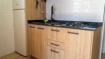 Een keuken met houten kastjes, een zwart aanrecht en een witte koelkast.