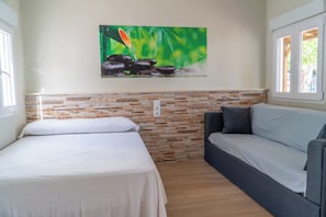 A room with a bed, a sofa, a wall-mounted painting, and a window.