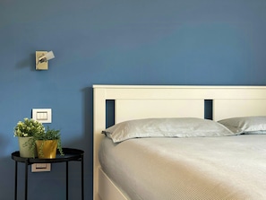 A bedroom with a bed, a nightstand with a plant, and a wall switch. - View over Lake Caldonazzo with large terrace (pergine valsugana)