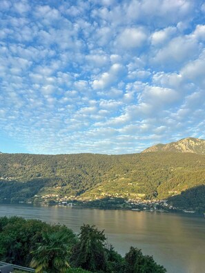 A lake surrounded by forested hills with a small settlement near the water's edge. - View over Lake Caldonazzo with large terrace (pergine valsugana)