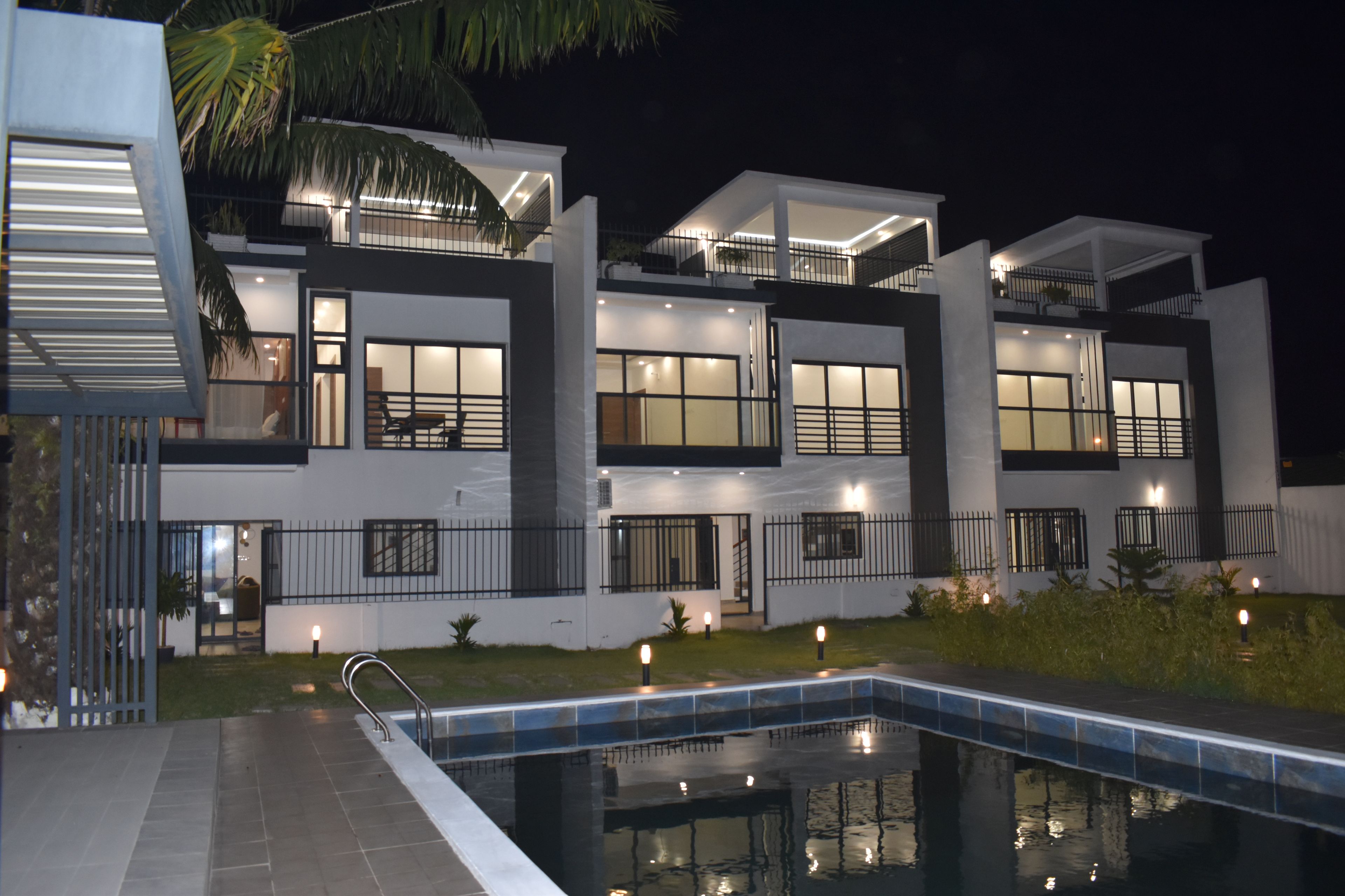 A modern two-story house with a swimming pool, featuring multiple balconies and large windows.