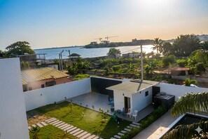 A rooftop terrace with a view of the sea, a small garden, and a modern building structure.