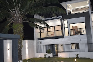 A modern two-story building with a balcony, large windows, and a well-lit entrance.