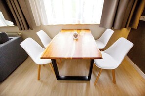 A dining area with a rectangular table, four white chairs, and a grey sofa. - Schöne, moderne Wohnung in Stadtnähe (Würzburg)
