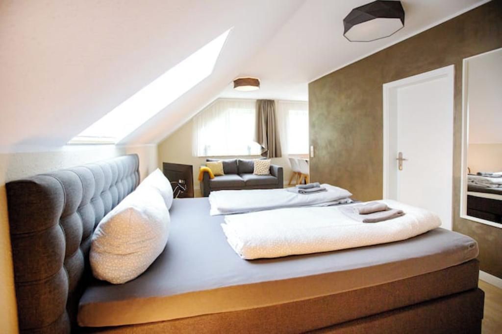 Ein modernes Schlafzimmer mit einem großen Bett, einer Couch und einer Essecke.