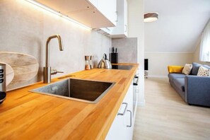 A modern kitchen with a wooden countertop, stainless steel sink, and a built-in range hood. - Schöne, moderne Wohnung in Stadtnähe (Würzburg)