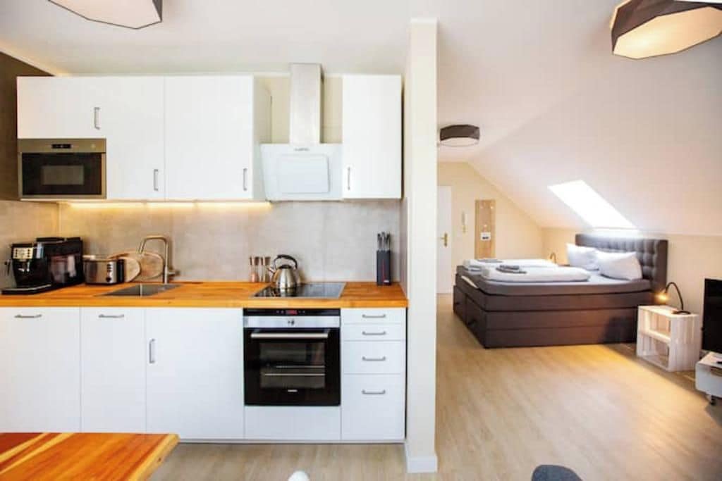 Eine kleine Küche mit weißen Schränken, einer Holz Arbeitsplatte und eingebauten Geräten.