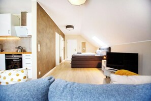 A modern bedroom with a bed, a TV, and a kitchenette in the background. - Schöne, moderne Wohnung in Stadtnähe (Würzburg)