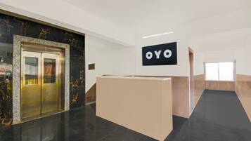 A reception area with a marble wall, a reception desk, and an elevator.