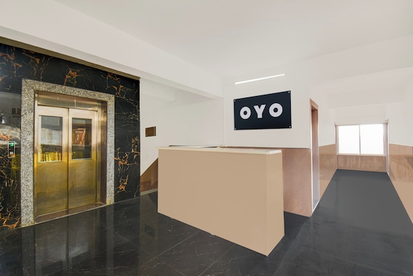 A reception area with a marble wall, a reception desk, and an elevator. - Super Hotel O Destiny Inn (Pune)