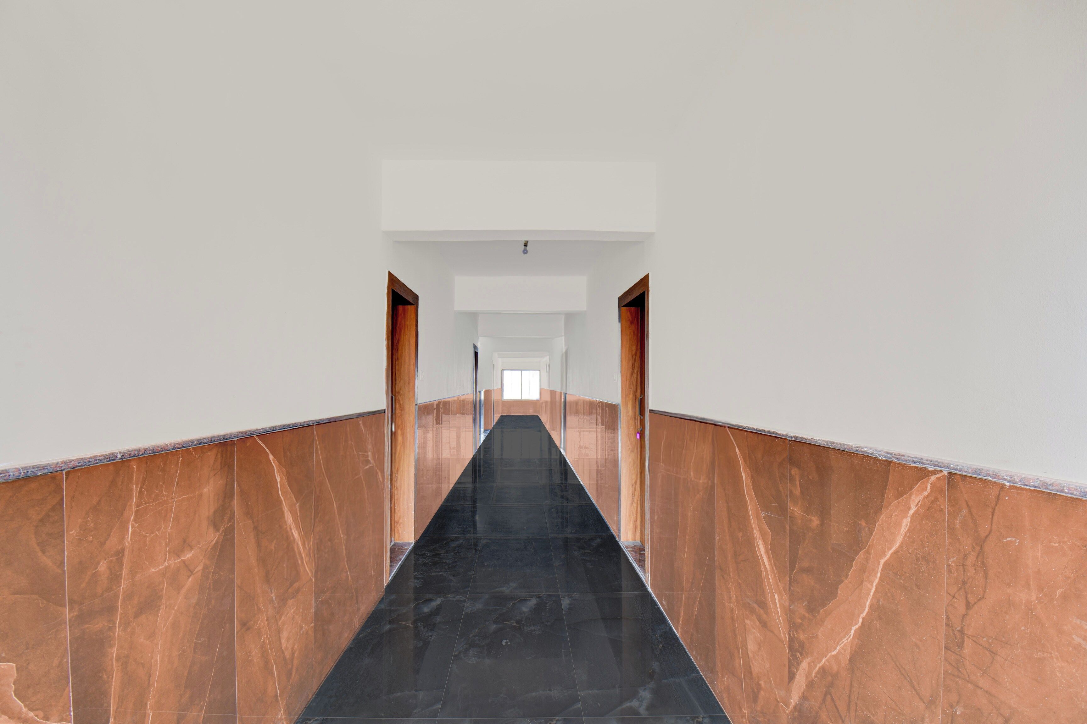 A corridor with marble walls and a black floor.