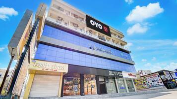 A multi-story building with a fitness center on the ground floor, a hotel named OYO on the second floor, and various shops on the ground floor.