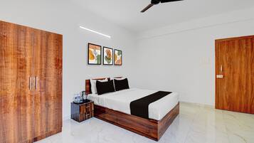 A bedroom with a bed, wardrobe, ceiling fan, and artwork on the wall.