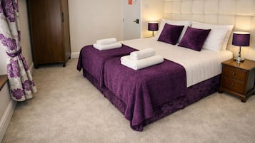 A hotel room with a double bed, two bedside tables, a wardrobe, and a bathroom door.
