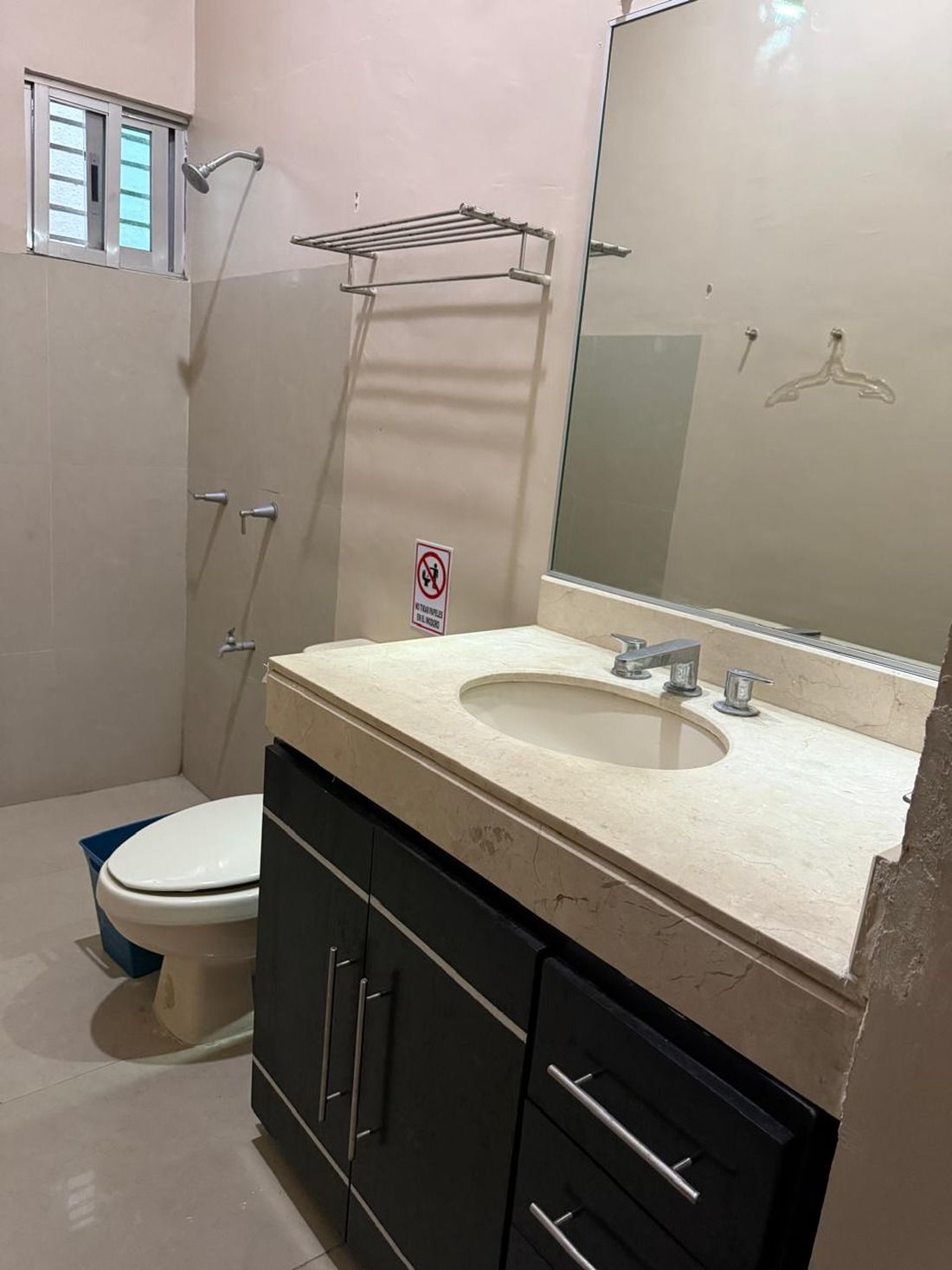 A bathroom with a toilet, sink, mirror, and shower.
