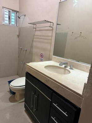 A bathroom with a toilet, sink, mirror, and shower. - Departamento 4 Gonzalo Guerrero (Mérida)