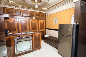 A kitchen with wooden cabinets, a refrigerator, and a tiled floor. - Via Kamla (Mumbai)