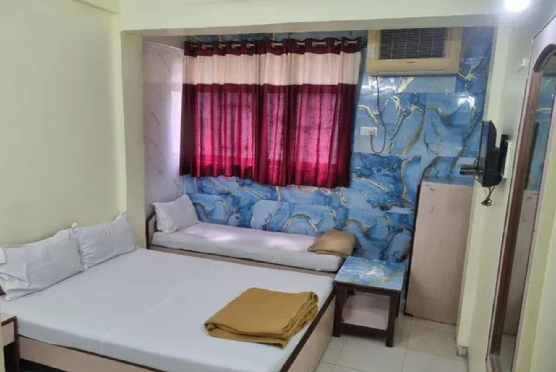 A room with a bed, a sofa, a small table, and a window with curtains.