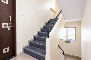 Una escalera con barandilla, una puerta con cerradura y un ventanal con letrero de salida de incendios.