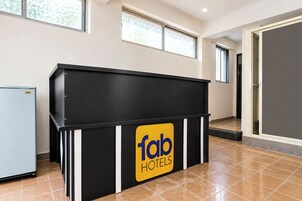 Una recepción con un letrero de 'fab hotels', una puerta a una habitación y un ventanal con vistas.