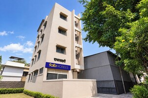A modern hotel building with a flat facade, multiple windows, and a sign indicating it is a FabHotels property.
